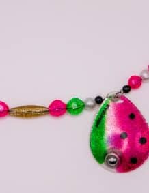 Colorful fishing tackle necklace featuring a pink and green lure pendant and beads.