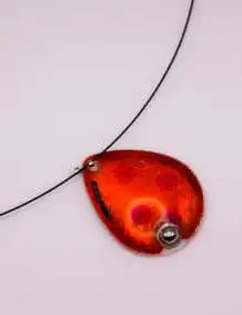 Red and black fishing lure with a metal ball, designed for freshwater fishing.