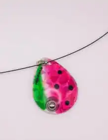 Bright pink and green fishing lure with black dots on a fishing line.